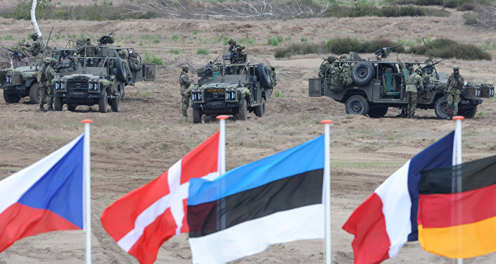 In this June 18, 2015,file photo flags wave in front of soldiers who take positions with their army vehicles during the NATO Noble Jump exercise on a training range near Swietoszow Zagan, Poland